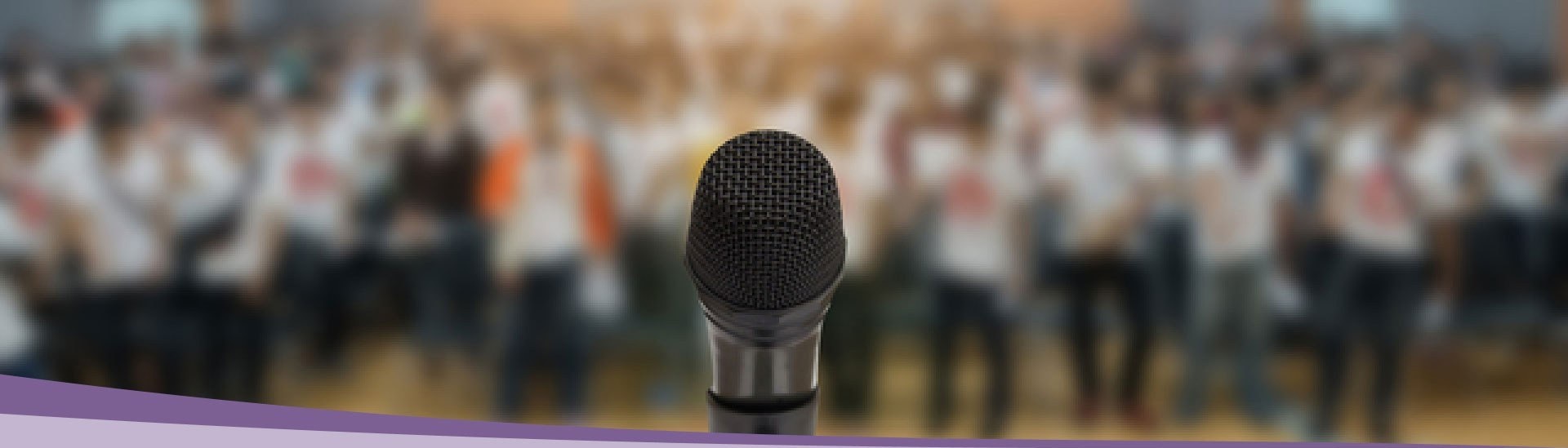 Closeup of a microphone with a blurry crowd in the background.